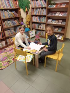 Dziewczynki rysują przy stoliczku w bibliotece