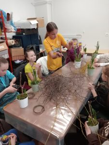 Dzieci tną gałązki na gniazdka na warsztatach florystycznych