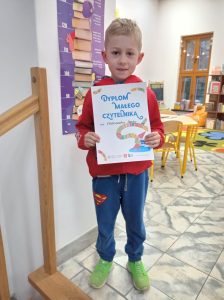 Chłopiec trzyma w rękach Dyplom Małego Czytelnika