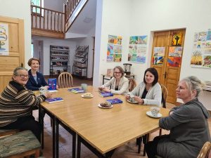 Kilka kobiet siedzi przy stole przy herbacie i rozmawia o przeczytanej książce