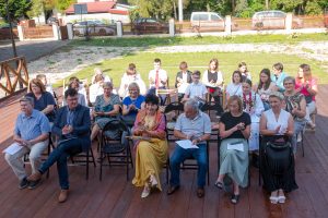 Publiczność siedzi na krzesłach wsłuchując się w czytane teksty Nad Niemnem