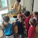 Bibliotekarka pokazuje dzieciom książeczki.