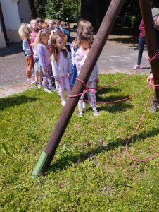 Dzieci na szkolnym podwórku słuchają prelekcji gościa