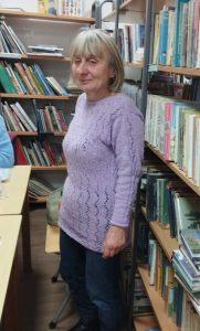 Kobieta prezentuje sweter wykonany własnoręcznie na drutach.