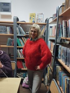 Kobieta prezentuje sweter wykonany własnoręcznie na drutach.